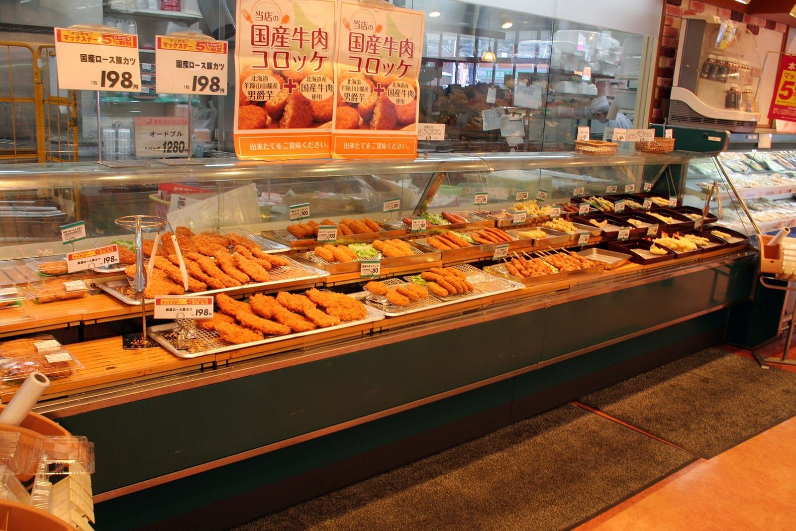 Japonya'daki bir süpermarketin kızartma ve kroket tezgahında, her tabağın önünde yen cinsinden fiyat etiketleri ve parlak fiyat panoları görülüyor.