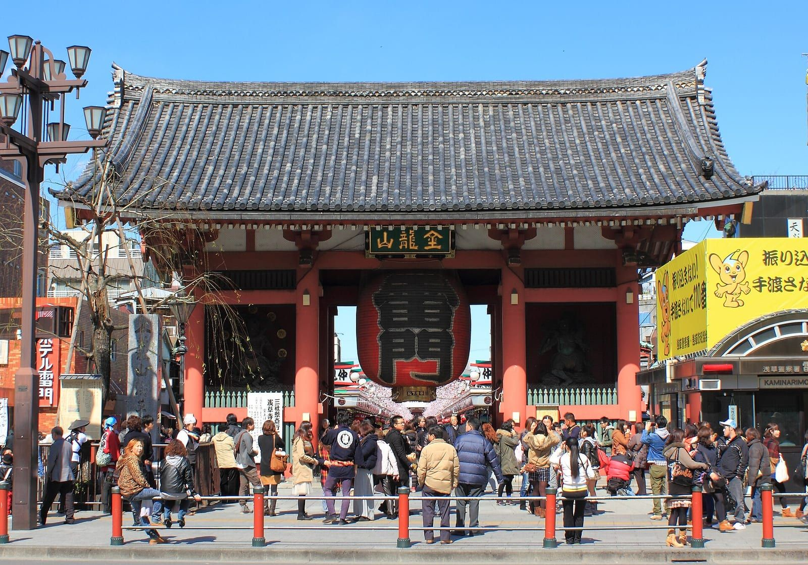 Asakusa'daki Sensō-ji Tapınağı'nın kırmızı fenerli Kaminarimon Kapısı, önünden geçen küçük görünen ziyaretçilerle birlikte gün ışığında görülüyor.
