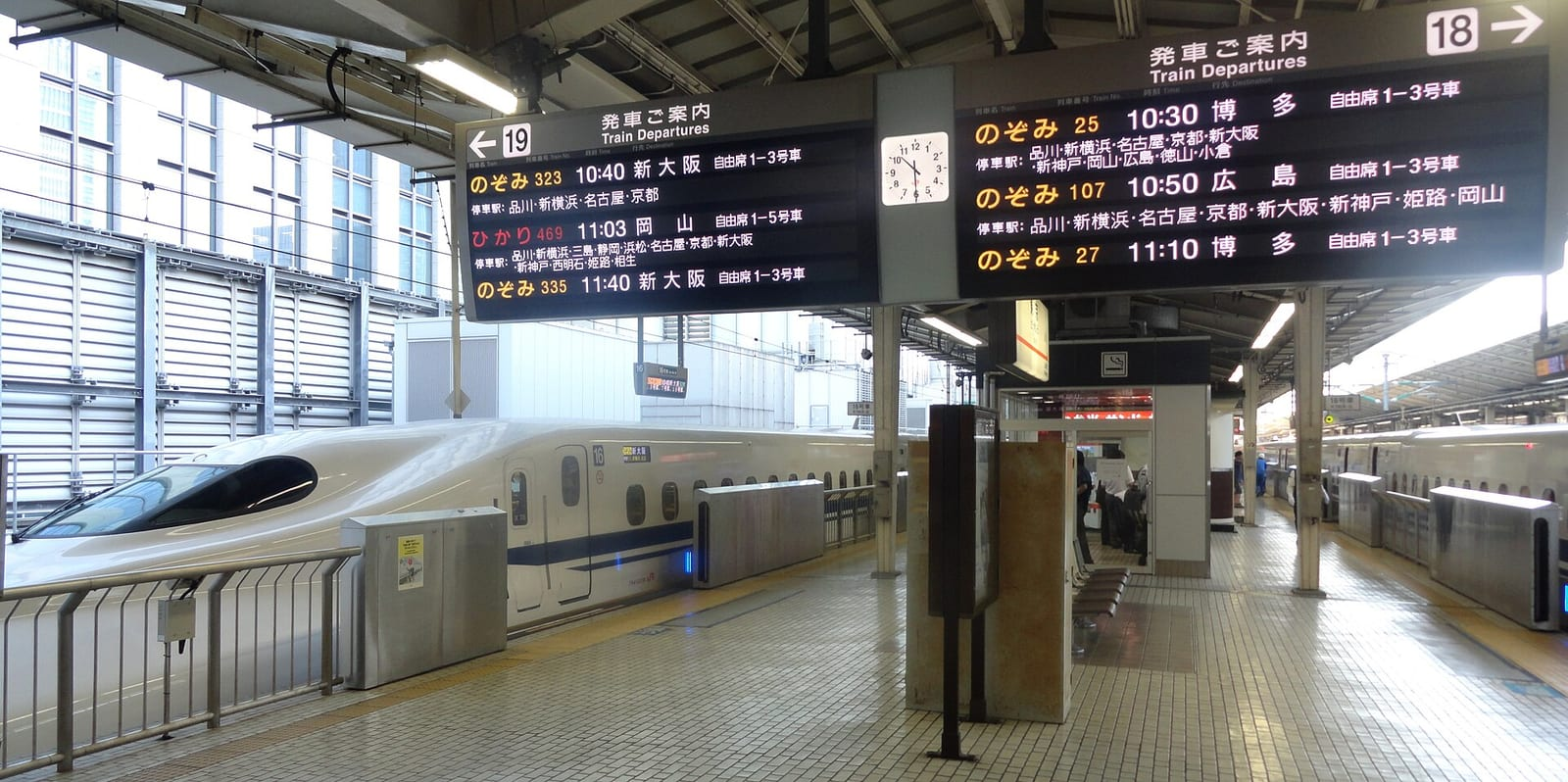 Tokyo İstasyonu'nda Shinkansen peronunda, kalkış saatlerini gösteren tabelaların altında bekleyen Nozomi trenleri görülüyor.