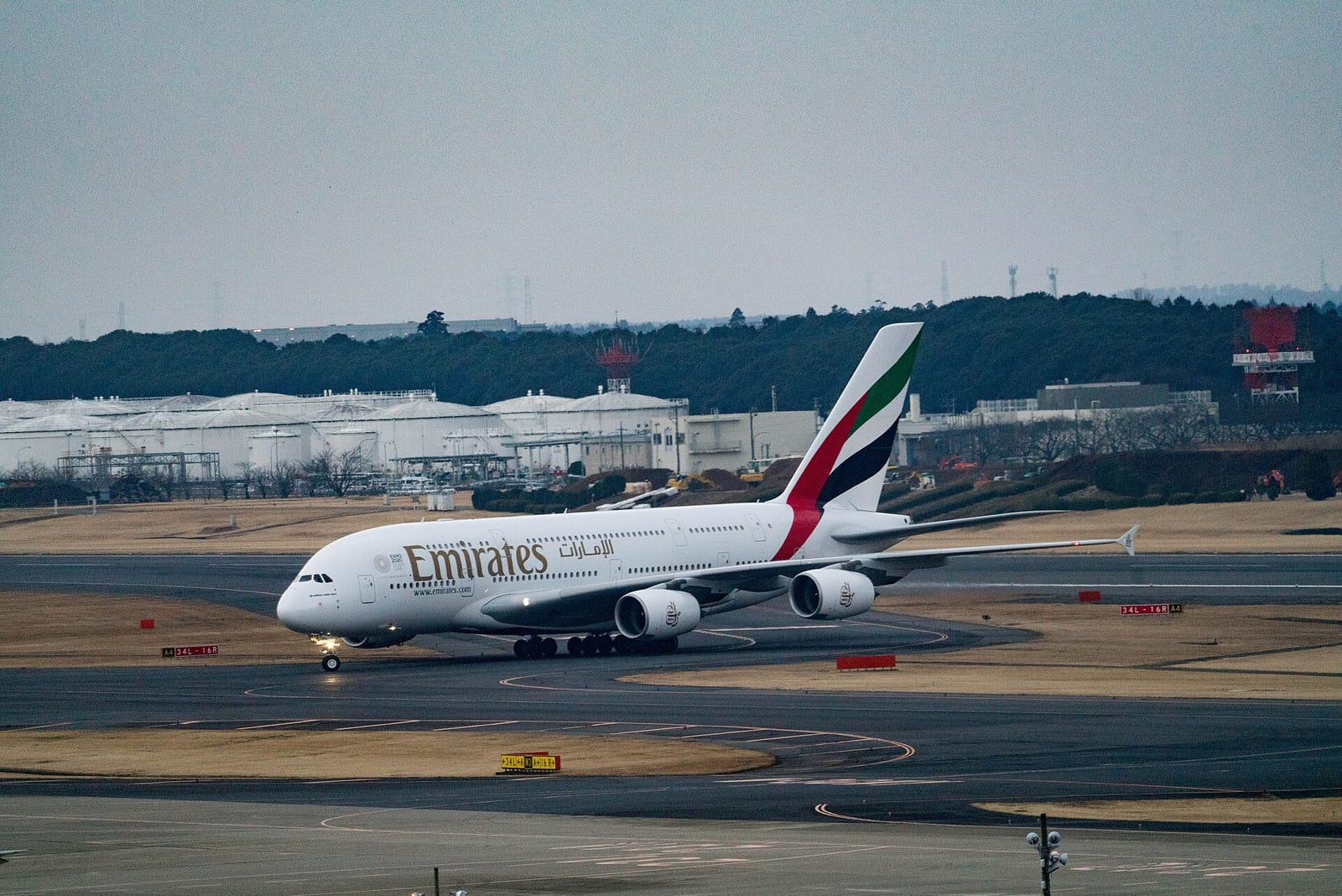 Emirates'in beyaz renkli çift katlı Airbus A380 uçağı Tokyo Narita Havalimanı'nda pist üzerinde yavaşça ilerliyor.